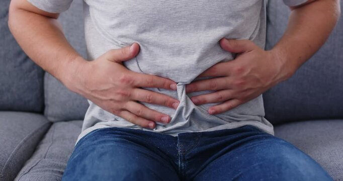 Sick man suffering from stomach ache close up, holding belly, feeling discomfort, with abdomen pain, gastritis symptom, indigestion problem, stomach discomfort or bad nutrition, medical spasm