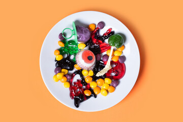 Assortment of Halloween candies on orange background. Top view
