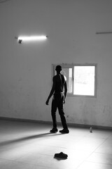 Fototapeta premium modèle africain devant une fenêtre dans une pièce sombre lors d'une journée ensoleillée en Afrique