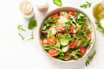Dash diet recipe. Green salad with baked chicken breast, fresh salad leaves and vegetables. Top view on white background.