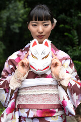 狐面を持ちポーズをとる着物の女性