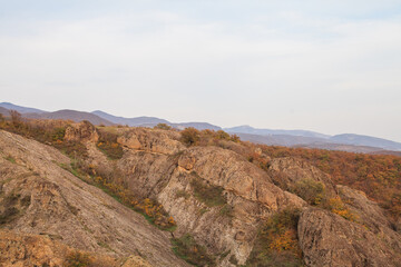 a panoramic view of autumn landscape with mountain hills surrounded by trees with yellow and red foliage at birtvisi canyon in georgia at a sunset light
