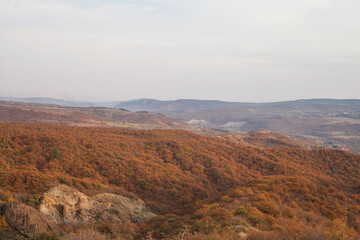Obraz premium a panoramic view of autumn landscape with mountain hills surrounded by trees with yellow and red foliage at birtvisi canyon in georgia at a sunset light