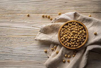 Chickpeas in a bowl on a wooden table and scattered on the table