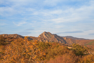 a panoramic view of autumn landscape with mountain hills surrounded by trees with yellow and red foliage at birtvisi canyon in georgia at a sunset light