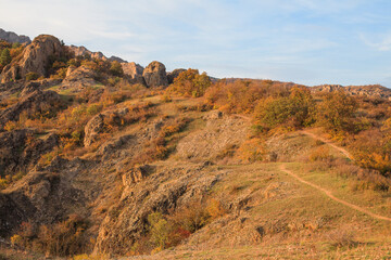 a panoramic view of autumn landscape with mountain hills surrounded by trees with yellow and red foliage at birtvisi canyon in georgia at a sunset light