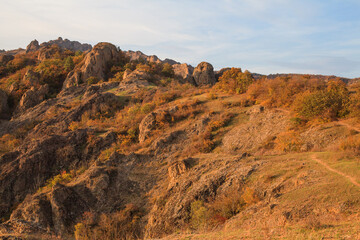 a panoramic view of autumn landscape with mountain hills surrounded by trees with yellow and red foliage at birtvisi canyon in georgia at a sunset light