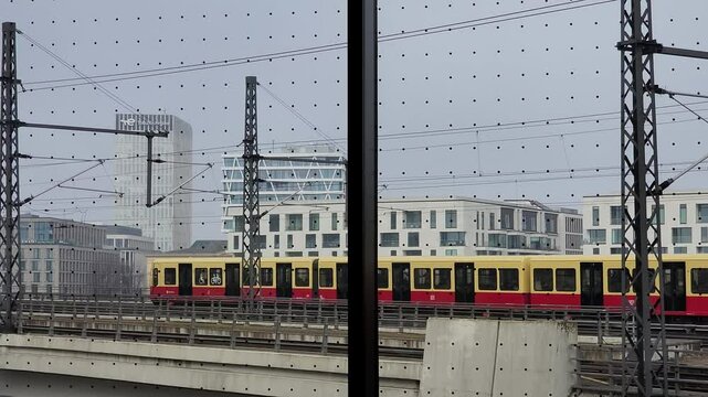 Red and yellow commuter train moves across a railway bridge in the city center. View from the window (186)