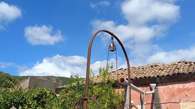Time lapse delle nuvole che corrono veloci sulle montagne dell'Etna, in primo piano un pozzo antico e il tetto di una casa di campagna
