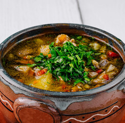 Delicious vegetable soup with herbs served in rustic clay pot