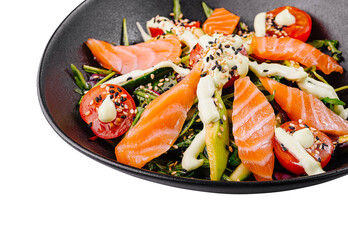 Delicious salad with salmon, avocado and cherry tomatoes being served on black plate