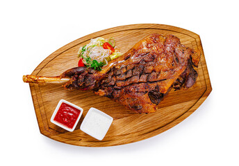 Roasted lamb shank with vegetables and sauces on wooden board