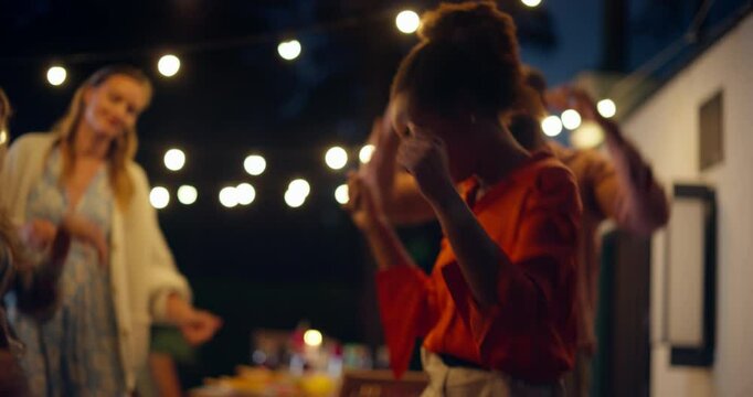 As the Evening Settles In, Diverse Female and Male Friends Dancing Beneath the String Lights, Moving to the Music with Joy and Energy. Backyard Comes Alive with Fun and Celebration - Powered by Adobe