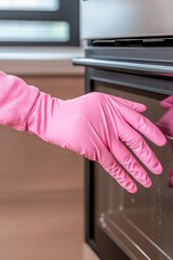 Obraz premium Hand in pink glove opening modern kitchen oven.