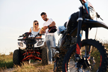 Obraz premium Man on motorcycle and woman is on the ATV, outdoors together