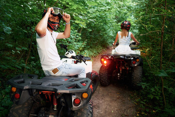 In the forest. Man and woman are on ATV outdoors