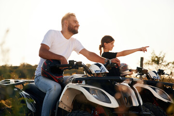 Girl is showing the way. Father and daughter are with ATV outdoors