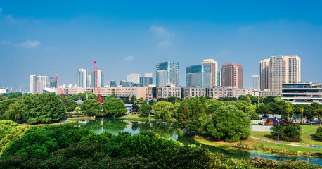 Obraz premium Vibrant City Skyline Surrounded by Lush Greenery at Daylight