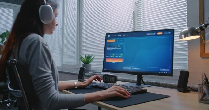 Adult woman in headphones types request in AI video generator on computer. PC screen shows artificial intelligence chatbot generating realistic video of dancing ballerina. AI video creation technology