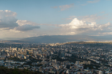A breathtaking view of a sprawling city beneath a dramatic sky at sunset from a scenic vantage point