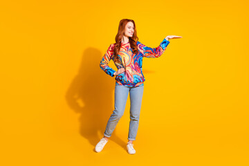 Photo of cheerful nice girl wear trendy print clothes demonstrate empty space isolated on bright yellow color background