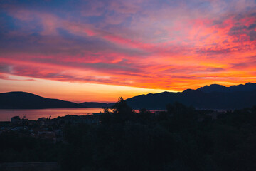 Vibrant sunset over serene mountains and calm waters reflecting colorful sky at twilight