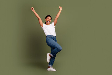 Full size photo of nice young woman raise fists empty space wear white t-shirt isolated on khaki...