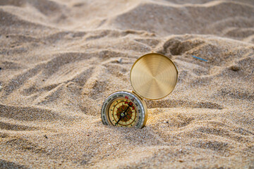 golden compass buried in the sand travel and tourism concept
