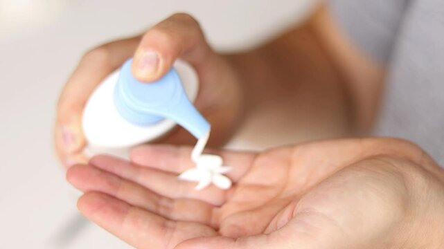 Close up of female hands appalling creme moisturizer on her hands. Blurry background 