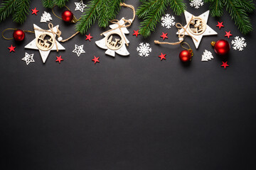 Christmas tree with holidays decorations at black background. Wooden toy decorations. Flat lay with...