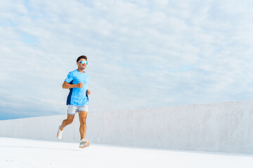 A Man Runs Energetically on a Bright White Rooftop During a Sunny Day With Scattered Clouds