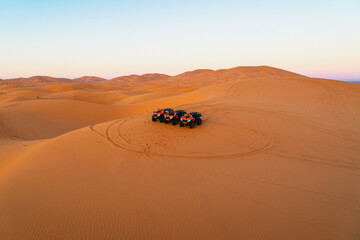 Dune adventure at sunset with multiple ATVs parked in the serene Sahara desert landscape