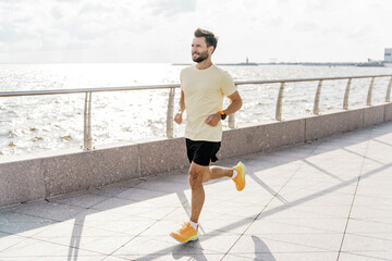 A Man Jogs Along a Coastal Promenade During a Bright Day With a Gentle Breeze and Serene Views of...