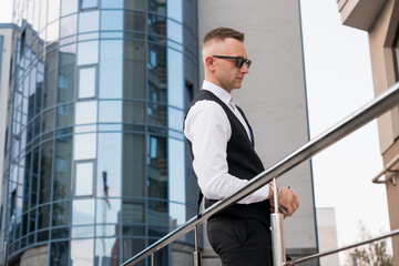 Stylish businessman in modern urban setting contemplating life in front of glass building