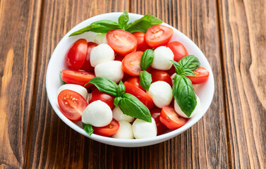 Basil leaves , cherry tomatoes and mozzarella cheese . In bowl food photography