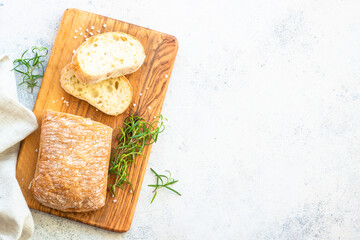 Italian ciabatta bread on wooden board. Top view on white table with copy space.