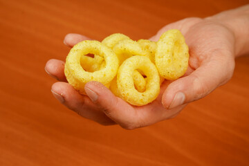 Man holds onion ring. Eating onion rings. Onion ring. Deep fried onion rings. Snack for beer. Fast food. Junk food. Cooked tasty appetizer meal. Fried rings. Corn onion rings. Unhealthy food.