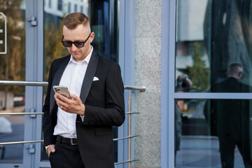 Sleek Urban Professional in Modern Attire Engaging with Smartphone Outside a Contemporary Building