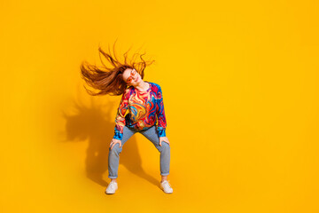 Full size photo of positive adorable girl dressed print shirt dancing in sunglass fluttering hair isolated on yellow color background