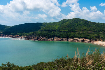 Obraz premium Serene Coastal Views: Lush Green Hills and Tranquil Waters Under a Blue Sky