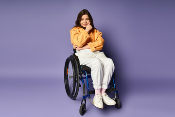 Trendy woman in casual attire sits in wheelchair against purple backdrop, hand on chin, gazing at...