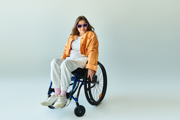 A young woman with long brown hair, wearing stylish casual clothing, sits confidently in a...
