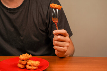 Man eating chicken nuggets. Chicken nuggets on plate. Chicken nuggets with ketchup. Fast food. Junk food. Unhealthy lifestyle. Calories. Obesity. American food. Eating with fork.