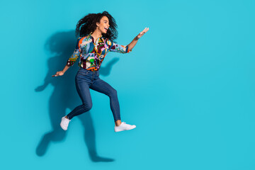 Photo of cheerful positive girl wear trendy clothes fly air look empty space isolated on blue color...