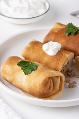 Savory pancake rolls stuffed with ground meat, isolated on white background