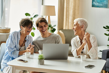 Three joyful family members share laughter and connection over a laptop in their warm living space.