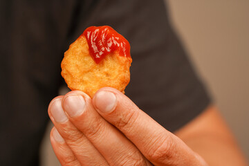 Fast food. Junk food. Chicken nuggets with ketchup. Holding chicken nuggets. Man eating chicken nuggets. Unhealthy lifestyle. Calories. Obesity. American food.