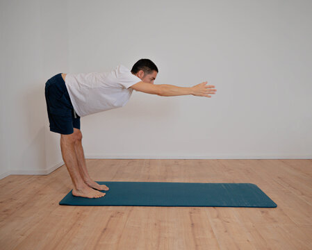 Caucasian Latino male in Ardha Uttanasana posture during a yoga session at home.