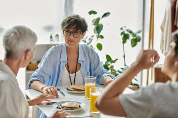 A joyful LGBTQ family shares a warm breakfast, filled with laughter and love, in their sunlit kitchen.