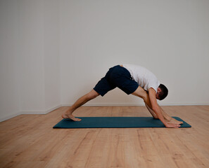 White Latino male performing a flexible posture in a yoga session at home.